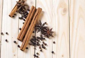 épices et herbes. ingrédients de la nourriture et de la cuisine. bâtons de cannelle, étoiles d'anis et grains de poivre noir sur fond de bois. photo