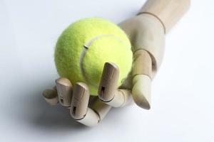 main en bois tenant une balle de tennis. photo