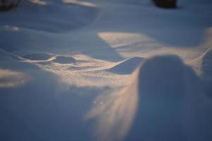 paysages enneigés et gros plan de neige dans les rayons du soleil. de l'herbe et des objets dans la neige. photo