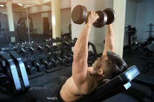 Le bodybuilder de l'homme de remise en forme musculaire est une séance d'entraînement avec des haltères dans une salle de sport photo