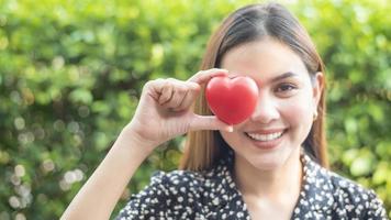 la main de la femme tient le coeur rouge, l'amour et le concept de soins de santé photo