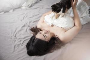 belle femme amoureuse des chats asiatiques joue avec un chat dans sa chambre photo