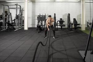 homme athlétique asiatique avec corde faisant de l'exercice dans une salle de fitness photo