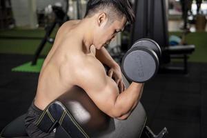 Le bodybuilder de l'homme de remise en forme musculaire est une séance d'entraînement avec des haltères dans une salle de sport
