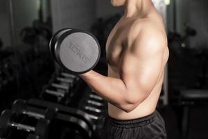 Le bodybuilder de l'homme de remise en forme musculaire est une séance d'entraînement avec des haltères dans une salle de sport photo