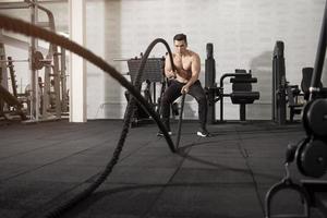 homme athlétique asiatique avec corde faisant de l'exercice dans une salle de fitness photo