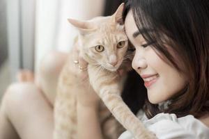 belle femme amoureuse des chats asiatiques joue avec un chat dans sa chambre photo