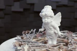 statue d'une fille ange avec des ailes sur une plaque blanche sur fond sombre photo