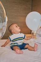 Portrait of happy baby boy asiatique de 6 mois assis sur le lit en jouant photo