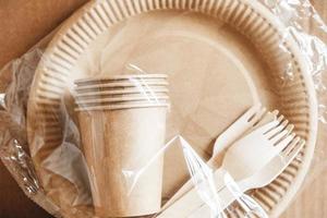 fourchettes en bois et gobelets en papier avec des assiettes sur fond de papier kraft. vaisselle jetable écologique. également utilisé dans la restauration rapide, les restaurants, les plats à emporter, les pique-niques photo