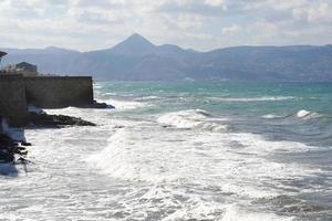 les vagues se brisant sur une plage de galets, formant un embrun. vague et éclaboussures sur la plage. les vagues se brisent sur les rochers. photo