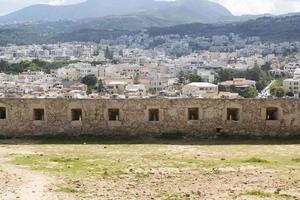 vue sur l'architecture grecque de la station balnéaire de la ville-port de réthymnon, construite par les vénitiens, depuis la hauteur du château de fortezza - forteresse sur la colline paleokastro. toits de tuiles rouges et montagnes en arrière-plan. Crète. photo