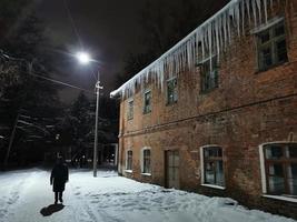 glaçons du soir d'hiver suspendus au toit à la lumière d'une lanterne photo