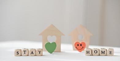 restez à la maison des lettres sur un dé près d'une maison de jouets en bois. photo
