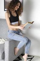 fille assise sur le canapé avec un livre. photo