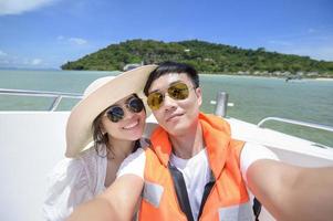 couple excité touriste prenant un selfie sur hors-bord avec une belle vue sur l'océan et la montagne en arrière-plan
