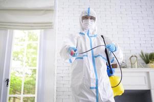 un personnel médical en costume d'EPI utilise un spray désinfectant dans le salon, une protection contre le covid-19, un concept de désinfection. photo
