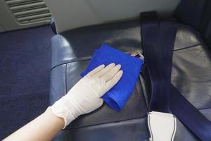 la main en gros plan porte des gants nettoyant l'avion pour la pandémie de prévention du covid-19 photo
