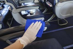 la main en gros plan porte des gants nettoyant l'avion pour la pandémie de prévention du covid-19 photo