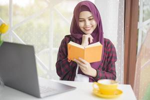 femme musulmane avec hijab travaille avec un ordinateur portable dans un café photo