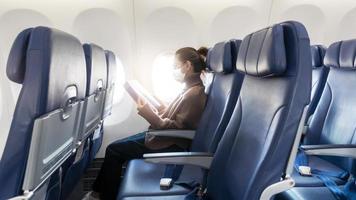 une jeune femme portant un masque facial voyage en avion, nouveau voyage normal après le concept de pandémie de covid-19 photo