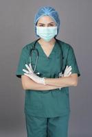 jeune femme médecin confiante en gommages verts porte un masque chirurgical sur fond gris studio photo
