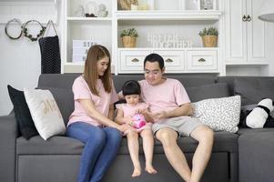 une famille asiatique enseigne à sa fille comment économiser de l'argent avec une tirelire, concept de planification financière photo