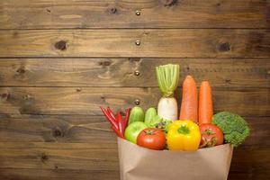 légumes dans un sac d'épicerie sur fond de bois photo