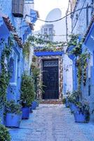 ruelle étroite de la ville bleue avec des plantes en pot menant à des structures résidentielles des deux côtés photo
