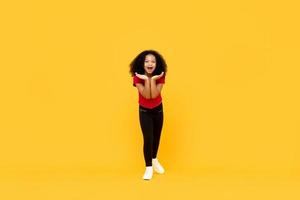 fille afro métisse dans un geste excité surpris avec les mains ouvertes isolées sur fond jaune photo