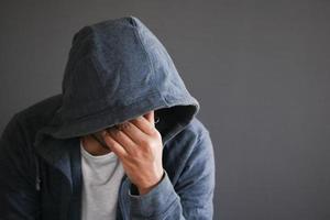 homme triste au visage de couverture de capot avec des mains isolées en noir. photo