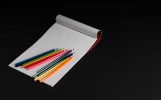 album pour dessiner et crayons de couleur sur fond noir, isolé. retour à l'école photo