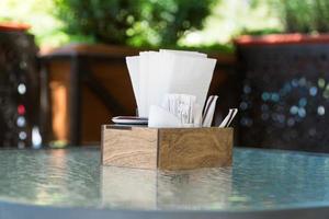 boîte avec des serviettes en papier sur une table en verre, gros plan. partie de la table café d'été en plein air photo