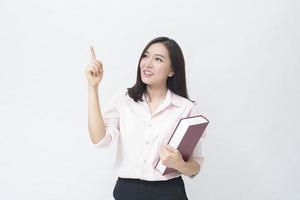 Portrait d'une belle étudiante en chemise rose tient un livre isolé sur fond blanc studio photo