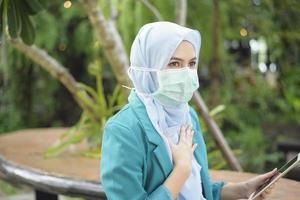 femme musulmane avec hijab porte un masque facial à l'extérieur photo