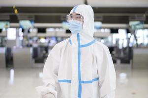 un homme asiatique porte un costume ppe à l'aéroport international, voyage en toute sécurité, protection contre le covid-19, concept de distanciation sociale photo