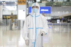 un homme asiatique porte un costume ppe à l'aéroport international, voyage en toute sécurité, protection contre le covid-19, concept de distanciation sociale photo