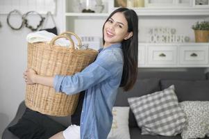 une femme de ménage heureuse porte un seau à linge pour la lessive dans la maison. photo