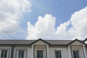 toit de tuiles grises sur maison devant un ciel bleu clair sur fond de journée ensoleillée. photo