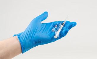 main dans la main tient une seringue et un vaccin sur fond blanc. concept de protection contre les coronavirus