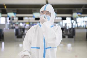 un homme asiatique porte un costume ppe à l'aéroport international, voyage en toute sécurité, protection contre le covid-19, concept de distanciation sociale