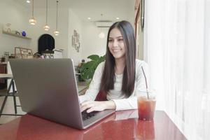 une jeune femme travaille avec son ordinateur portable dans un café photo