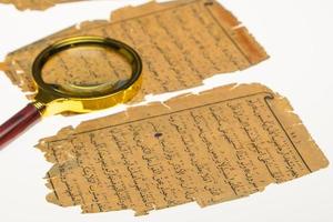 pages de livre avec un manuscrit arabe sur une table avec une lumière et une loupe. paléographie, l'étude de l'écriture arabe ancienne photo