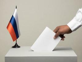urne avec le drapeau national de la russie. élection présidentielle. main jetant un bulletin de vote photo