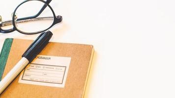 cahier de couverture en papier artisanal marron avec stylo et lunettes sur fond blanc isolé de bureau.