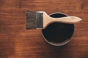 pinceau sur un pot avec de la peinture brune sur un fond en bois photo