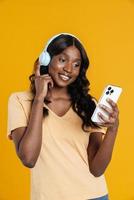 heureuse femme africaine envoyant des SMS par téléphone avec un casque photo