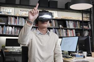 un travailleur masculin asiatique utilise un équipement de simulateur de casque vr pour visualiser le cyberespace 3d, afficher et toucher interactif, espace de travail numérique futuriste au bureau d'affaires, appareil gadget, expérience passionnante.