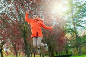 femme en manteau orange sautant dans le parc photo