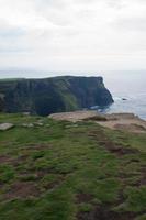 falaises de moher par temps nuageux. champs verts et eau calme. Irlande photo